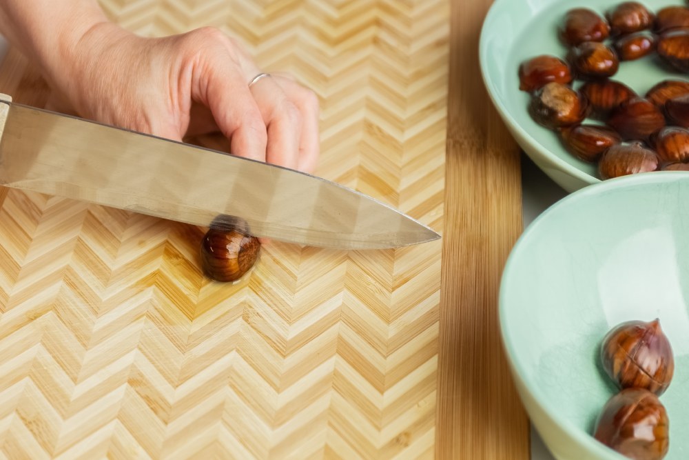 Kesme tahtası üzerinde kestaneler bıçakla çiziliyor.